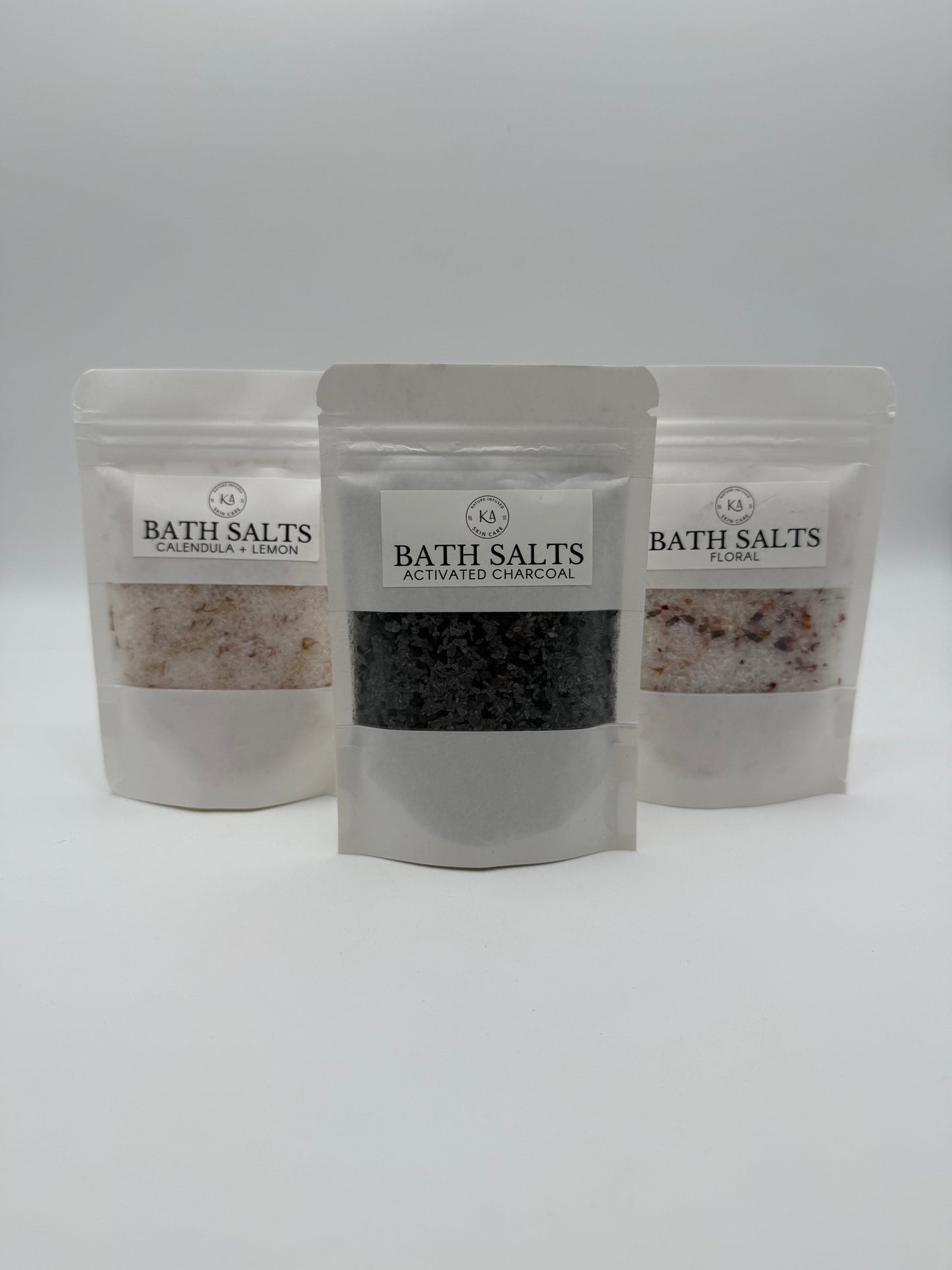 Three packages of bath salts with visible contents on a white background