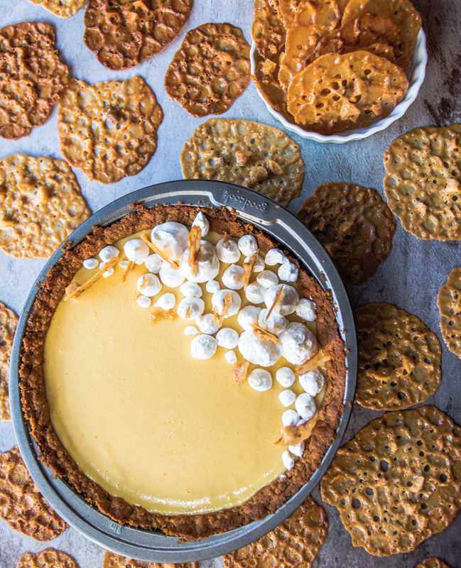 Small round dessert with white topping on a plate surrounded by crackers