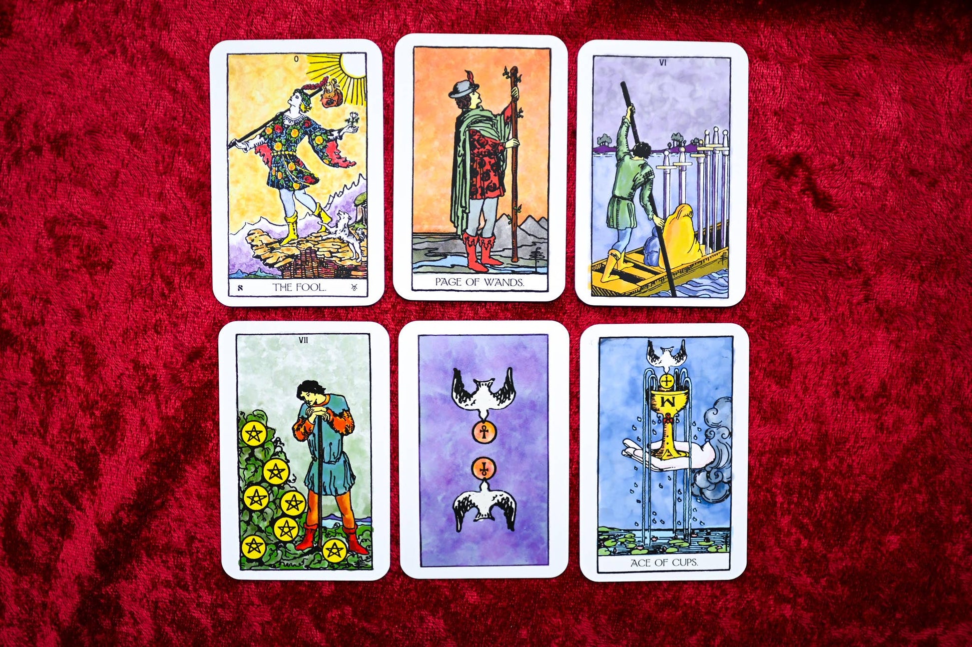 Six tarot cards displayed on a red textured surface