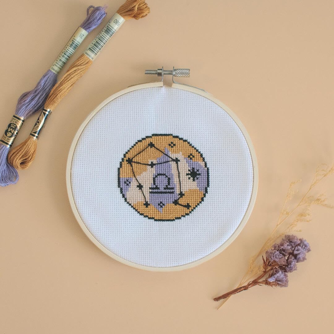 Embroidery hoop with a completed cross-stitch design on a beige background