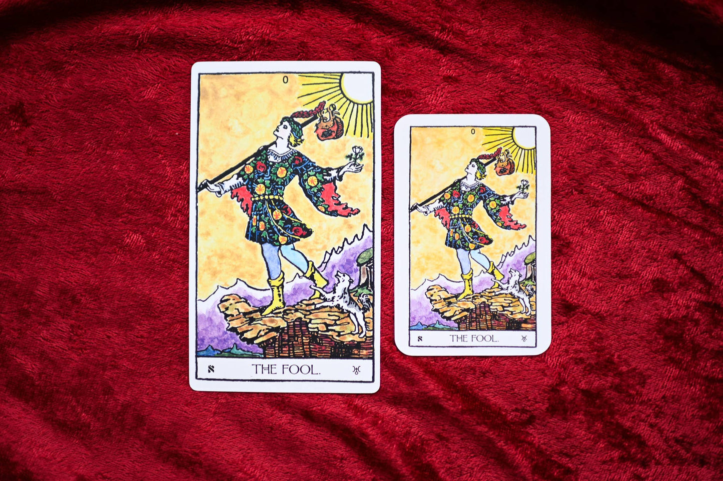 Two tarot cards titled 'The Fool' on a red fabric background