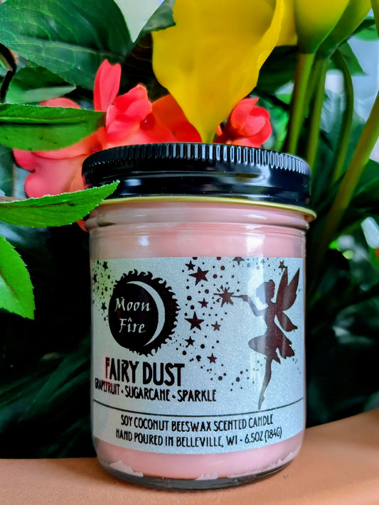 Candle jar labeled 'Fairy Dust' with decorative fairy elements on a floral background with Moonfire branding.