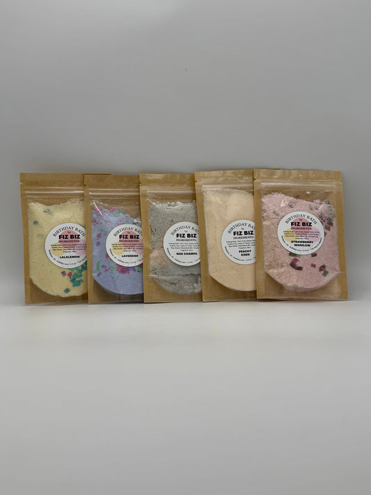 Five packages of Fiz Biz Birthday Bath Salts in various scents on a white background