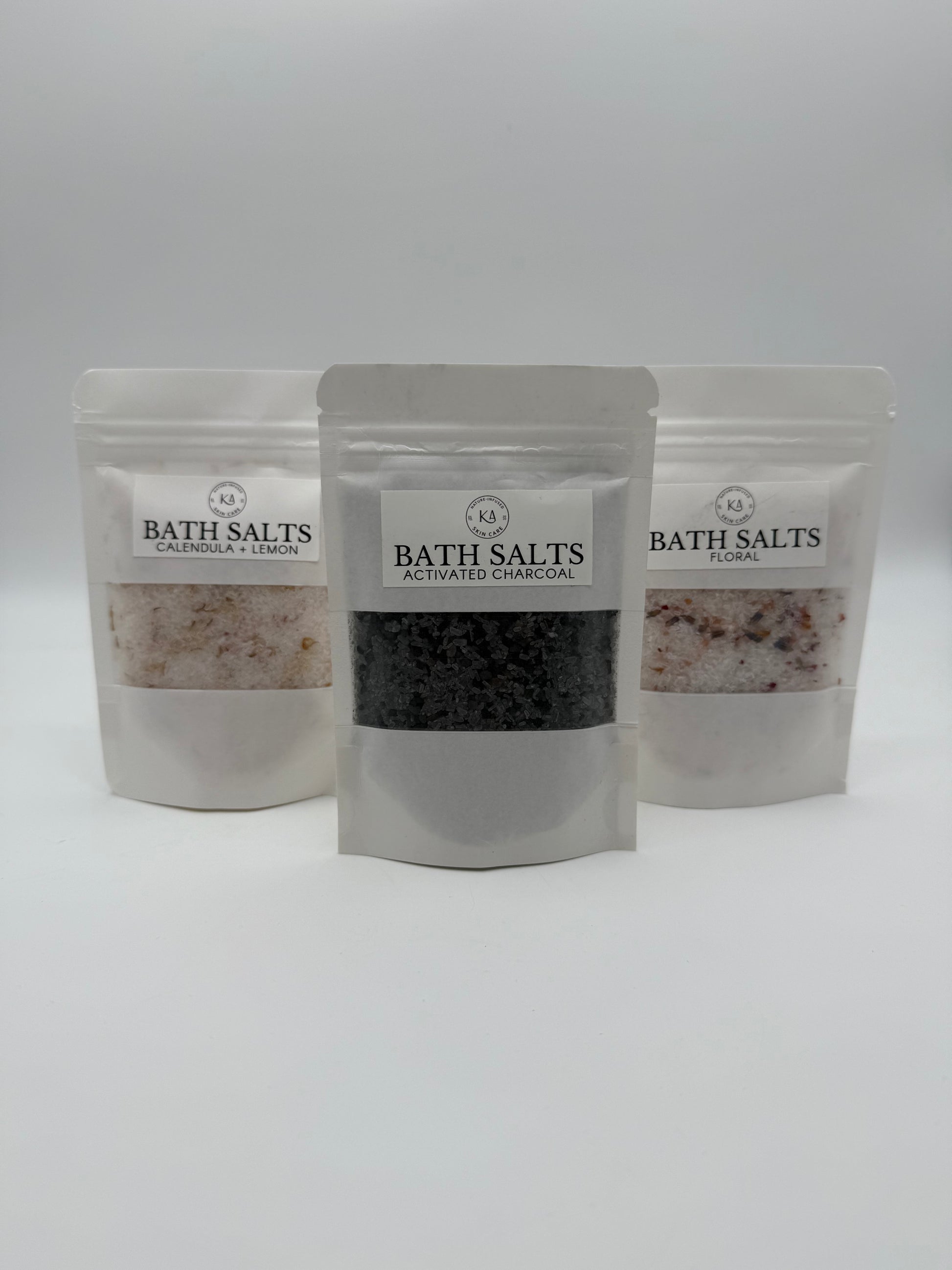 Three packages of bath salts with visible contents on a white background