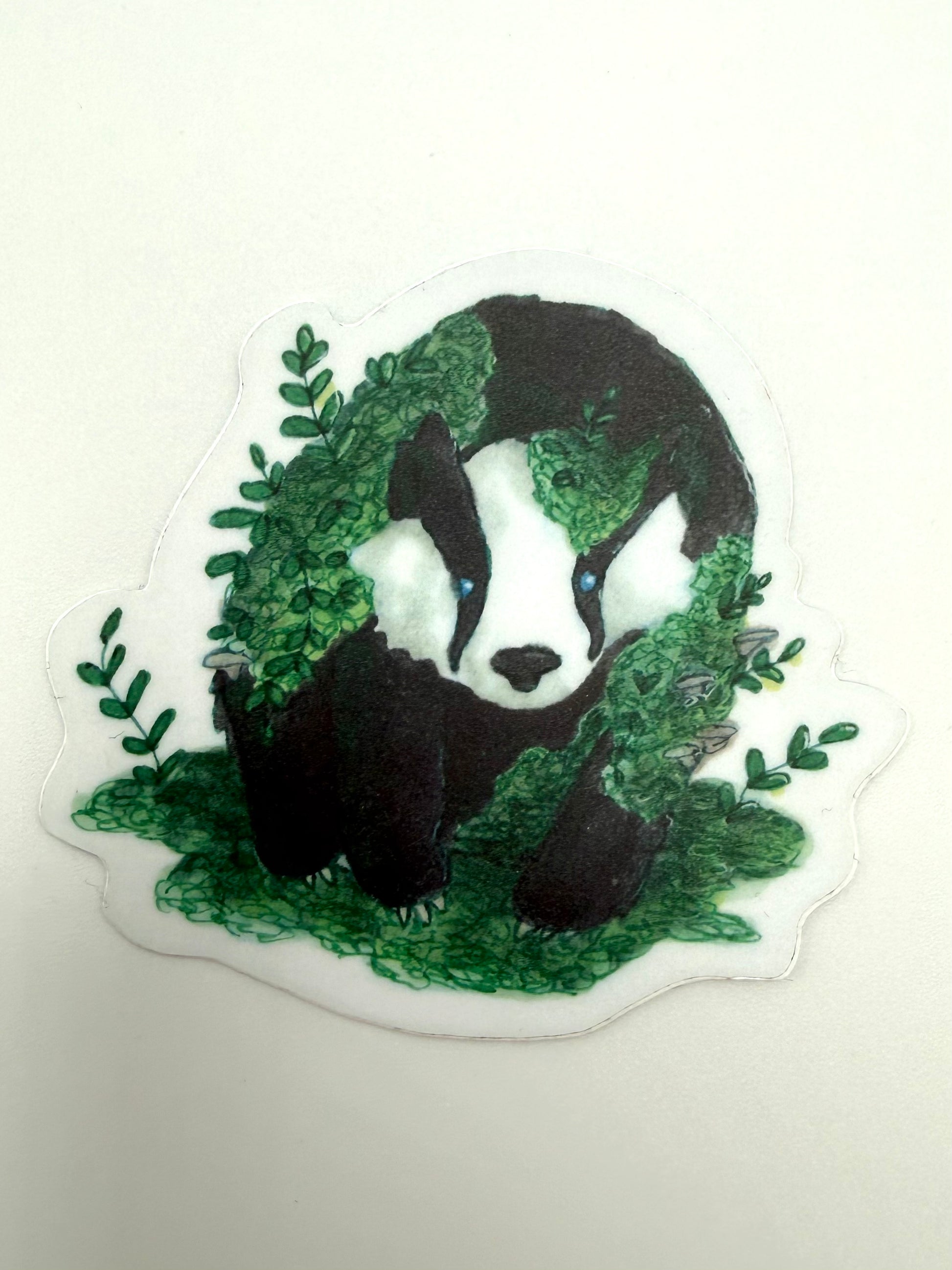 Sticker of a badger surrounded by green leaves on a white background